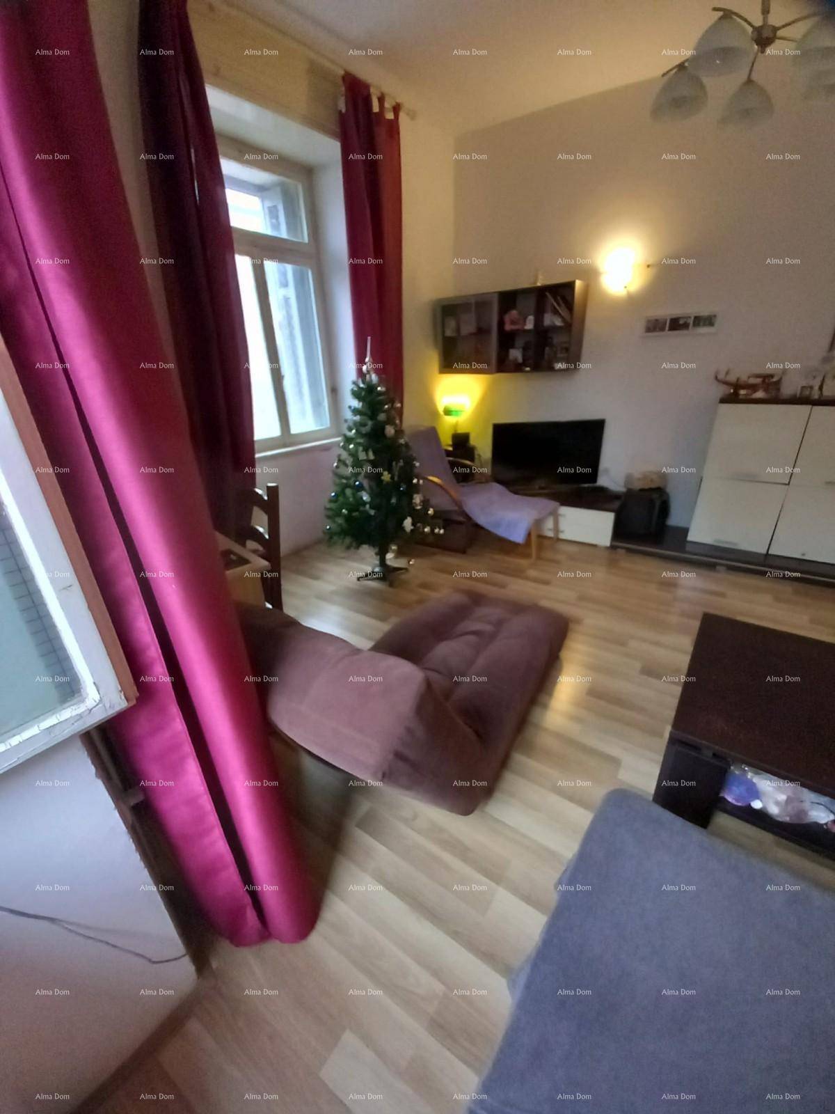 Gemütliches Wohnzimmer mit Holzboden, roten Vorhängen und einem kleinen Weihnachtsbaum.
