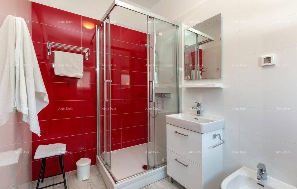 Helles Badezimmer mit Duschkabine, Waschbecken und roten Wandfliesen.