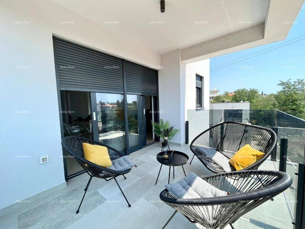 Möblierter Balkon mit Glasgeländer und Blick auf die grüne Umgebung.