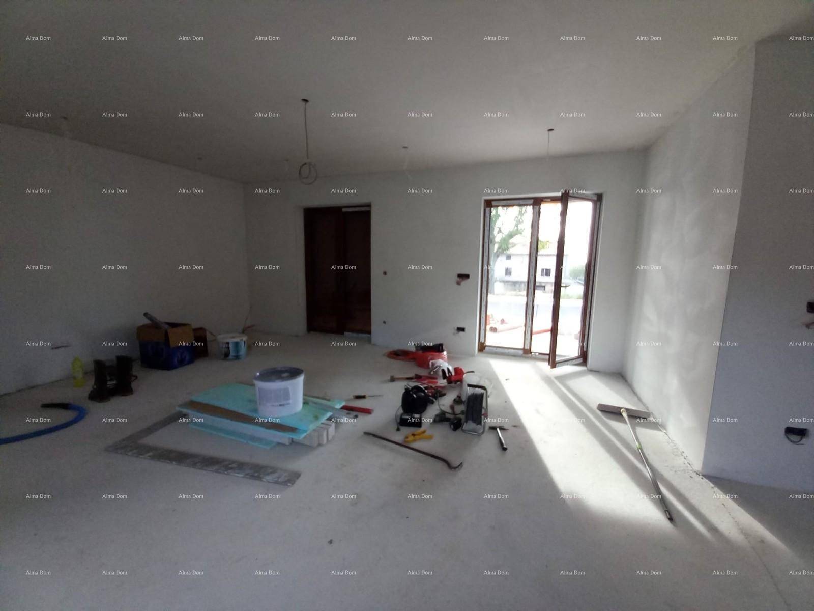 Geräumiger Innenraum im Rohbau mit viel Tageslicht und Baumaterialien.