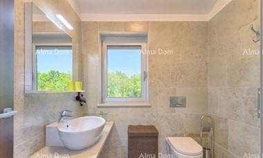 Helles Badezimmer mit Fenster, Waschbecken, Spiegel und WC in neutralen Farbtönen.