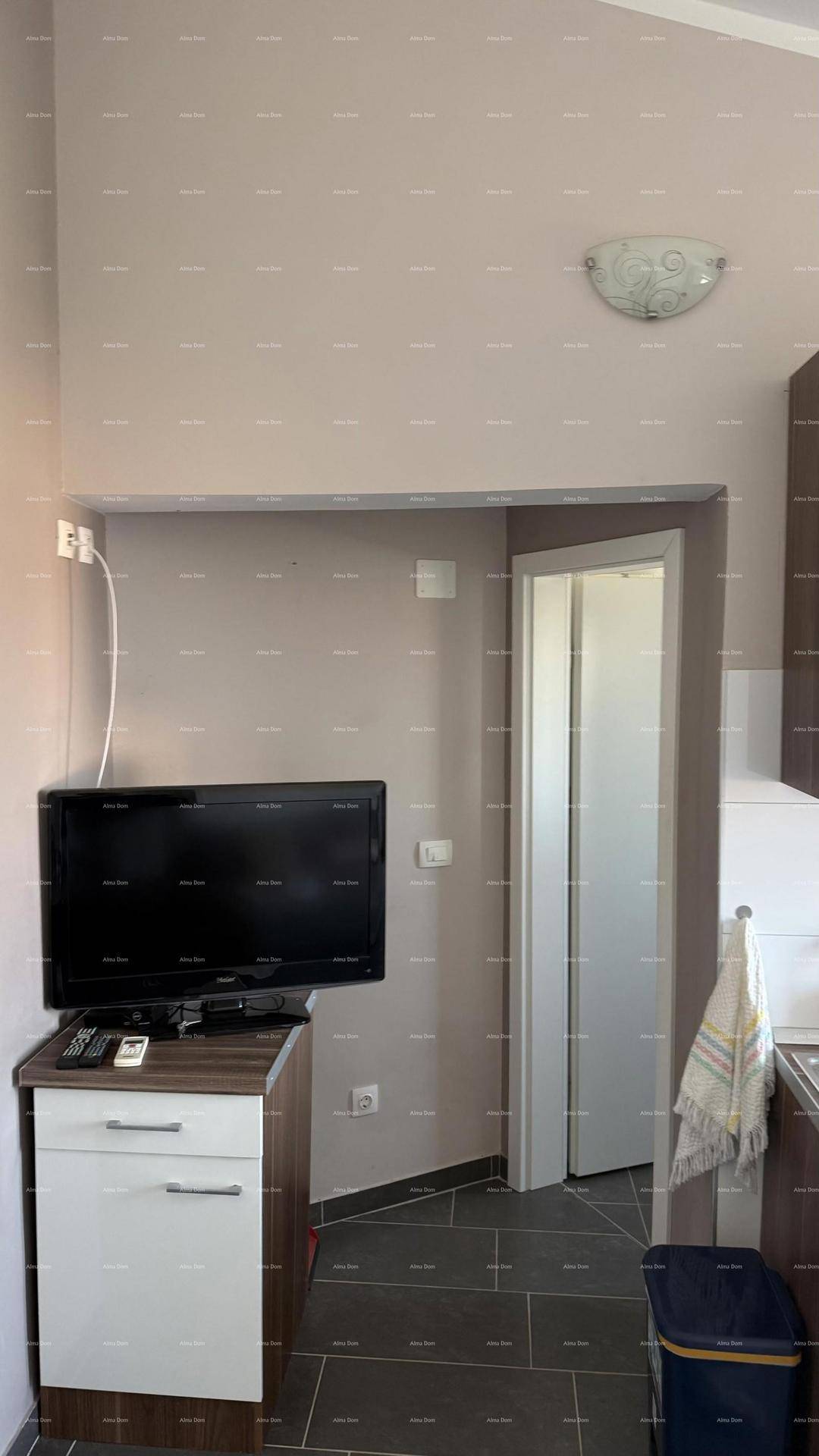 Gemütliche Ecke im Wohnbereich mit Fernseher auf einem Schrank und Zugang zu einem weiteren Zimmer.