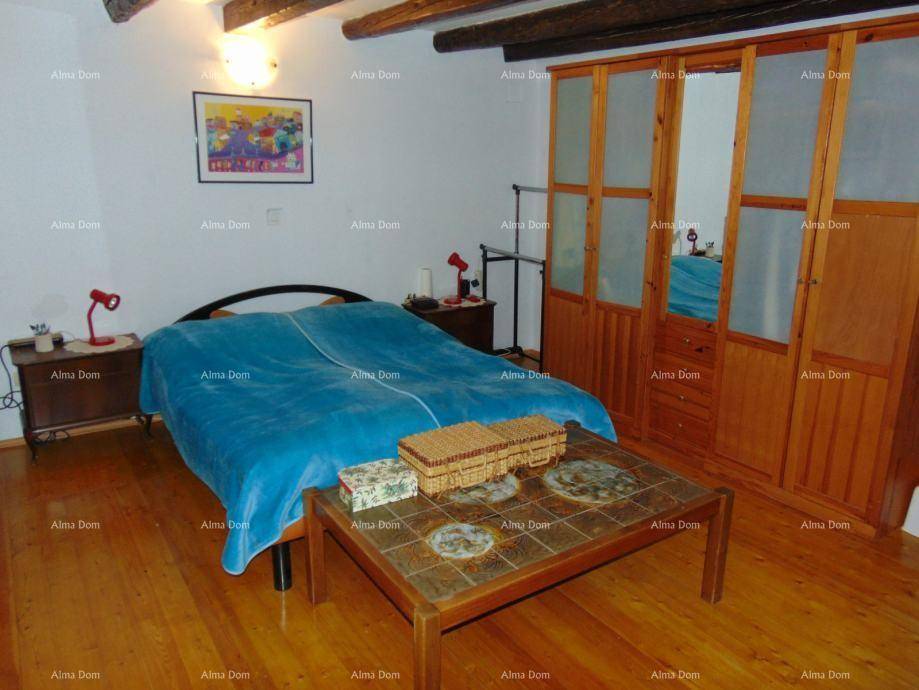 Schlafzimmer mit Holzboden, sichtbaren Deckenbalken und einem großen Holzschrank.