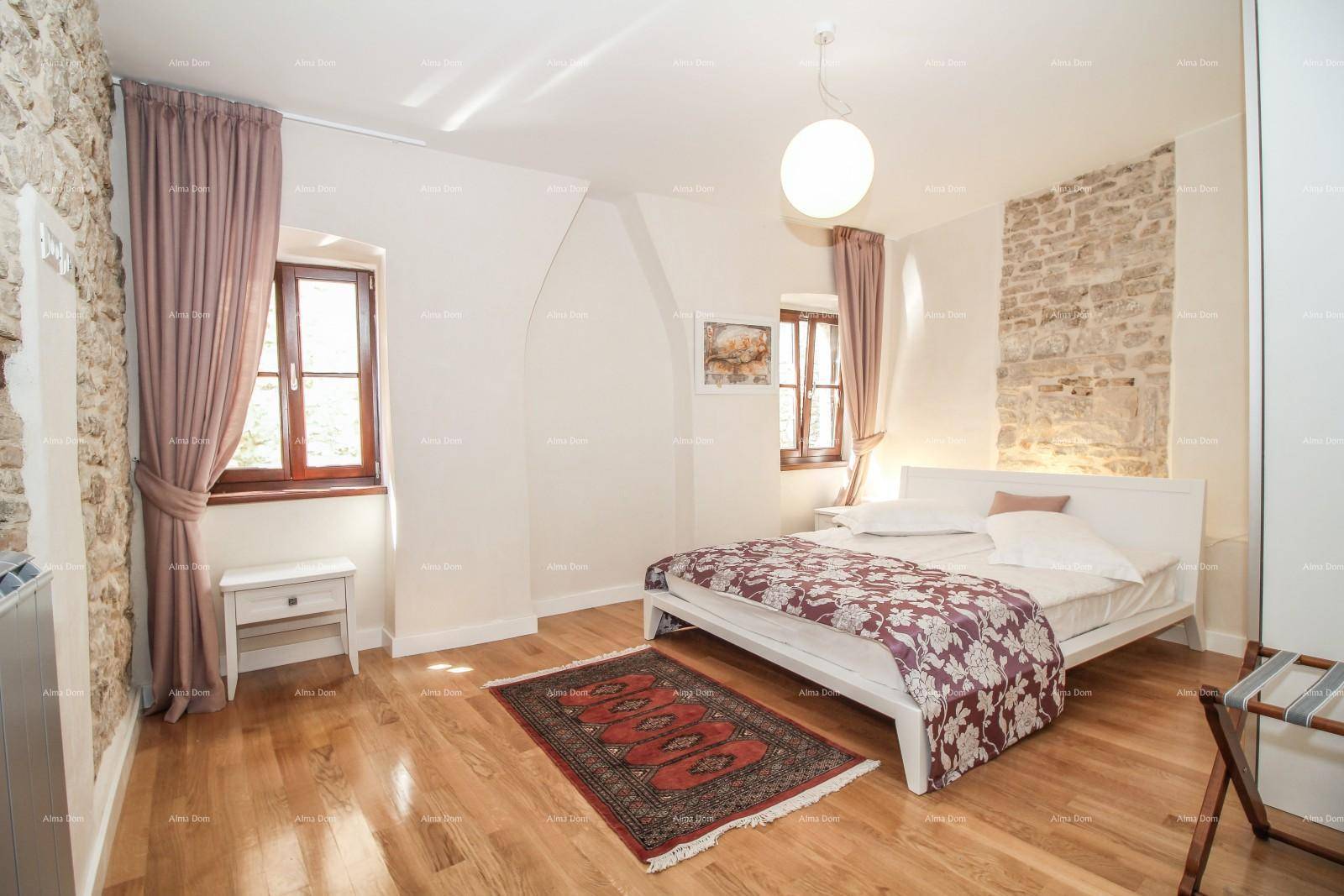 Schlafzimmer mit Holzboden, Doppelbett und freiliegender Steinwand, die rustikalen Charme verleiht.