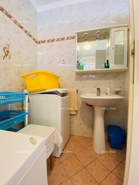 Kleines Badezimmer mit Waschbecken, Spiegelschrank und Waschmaschine, gefliest in warmen Tönen.