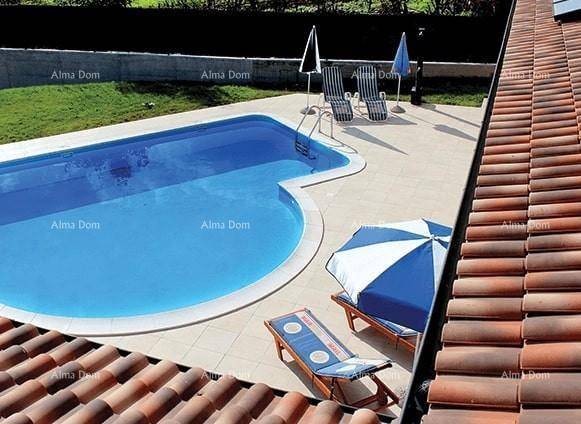 Blick von oben auf den Poolbereich mit Sonnenliegen und Schirmen, umgeben von Fliesen und Rasen.