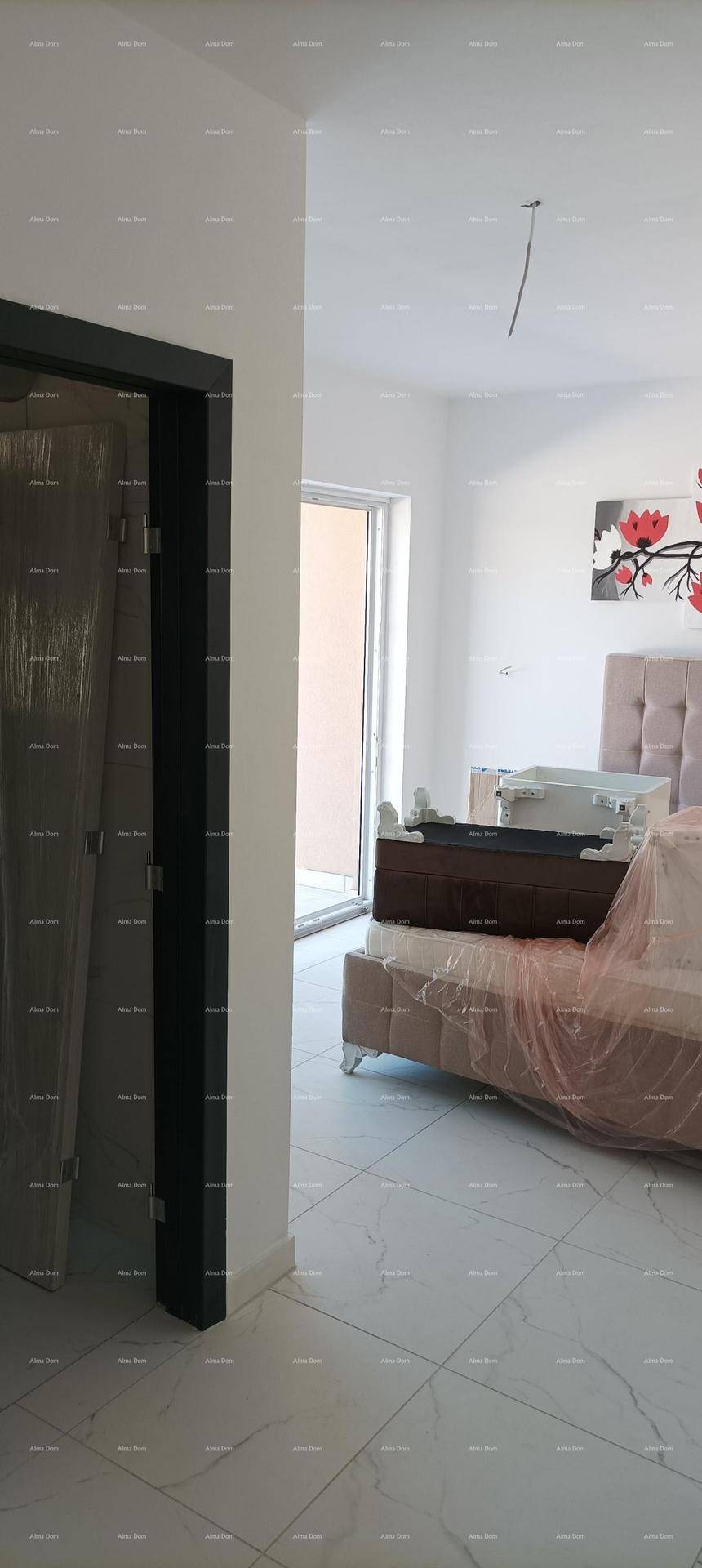 Schlafzimmer mit einem gepolsterten Bett und Blick auf einen Balkon durch die Tür.