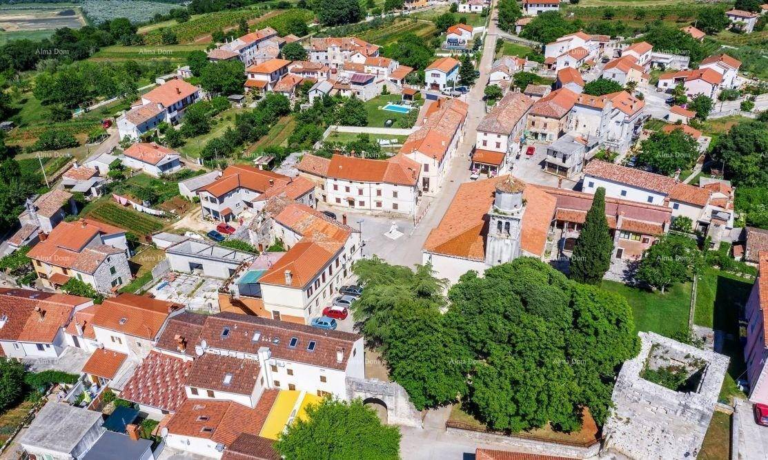 Luftaufnahme eines malerischen Dorfes mit traditionellen Häusern, roten Dächern und grüner Landschaft.