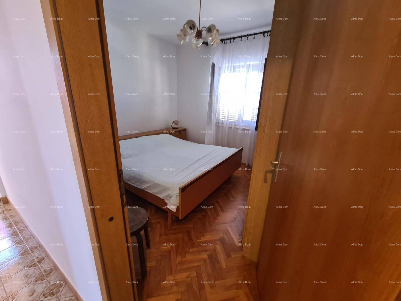 Schlafzimmer mit Parkettboden und einem Doppelbett, durch eine offene Tür sichtbar.