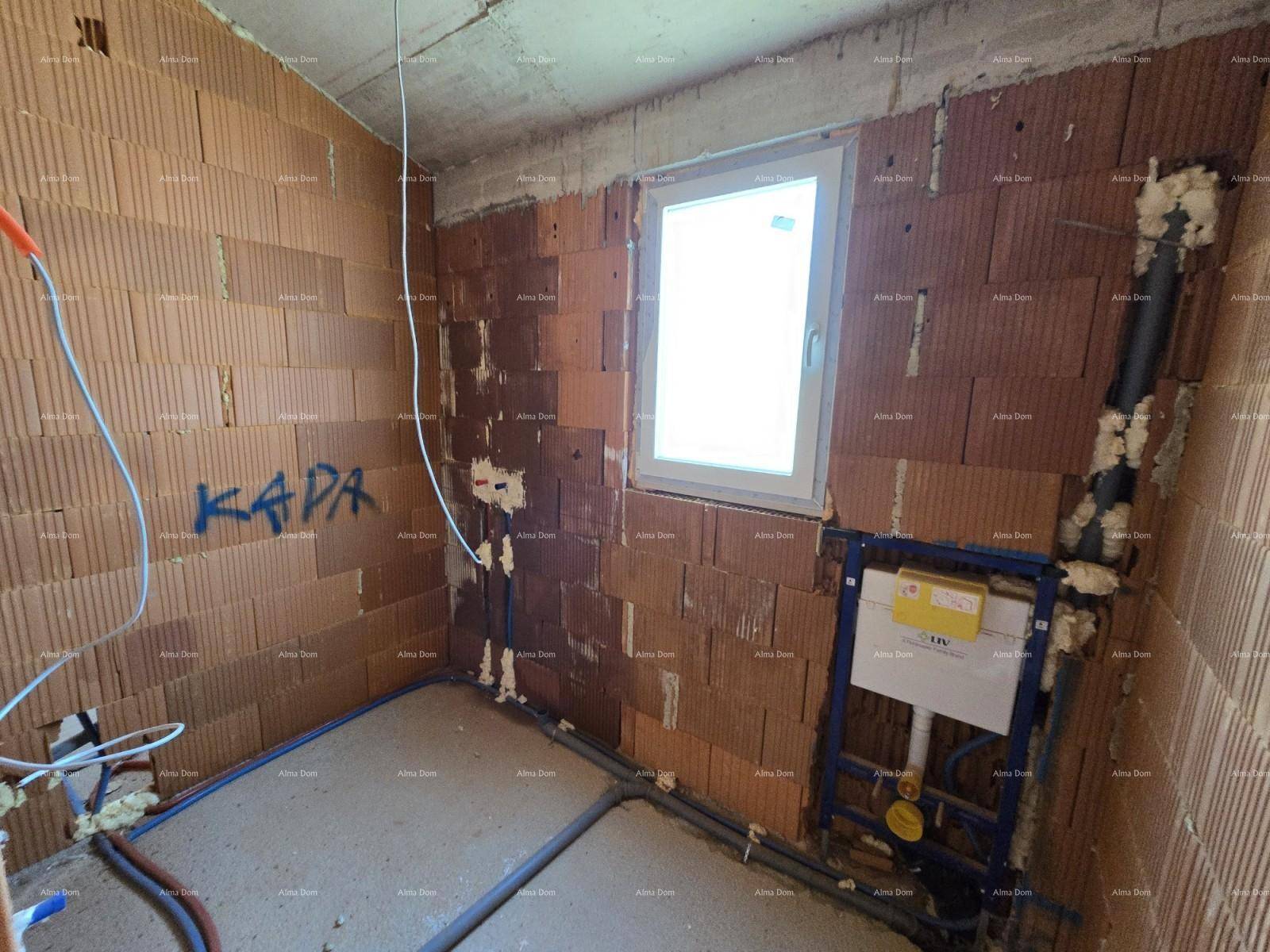 Badezimmer im Rohbau mit Fenster, Ziegelwänden und vorbereiteten Sanitärinstallationen.