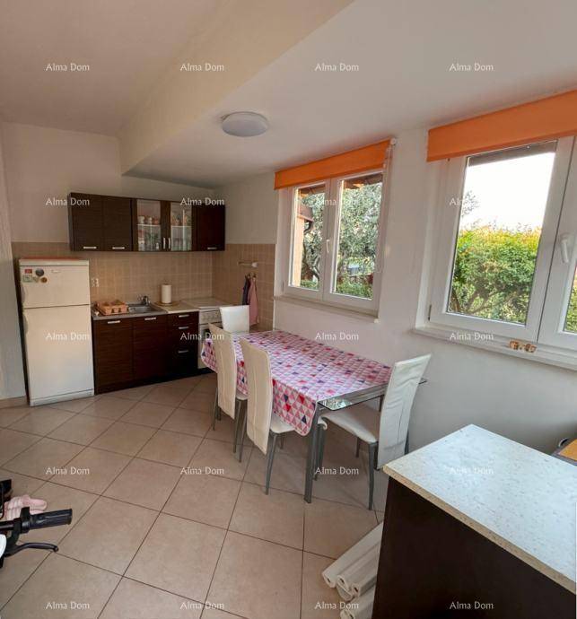 Funktionale Küche mit Essbereich, Fliesenboden und Blick ins Grüne durch die Fenster.