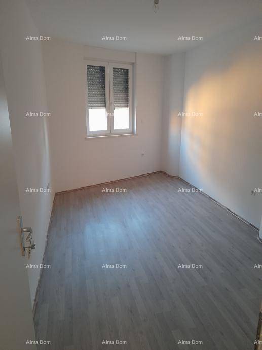 Leeres Schlafzimmer mit modernem Laminatboden und Fenster mit Rollladen, bereit zur Einrichtung.
