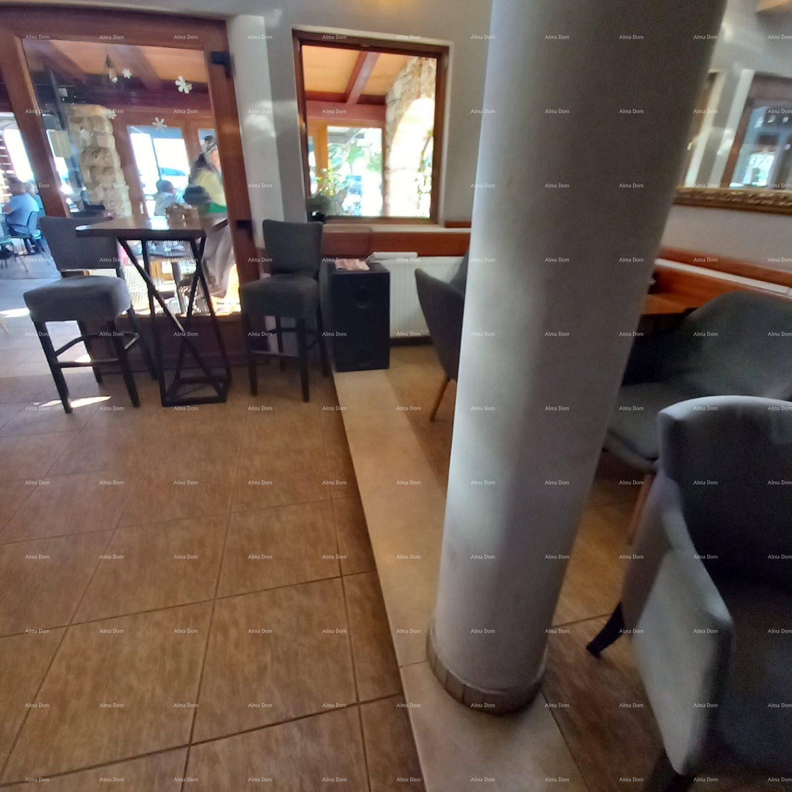 Gemütlicher Sitzbereich in einer Bar mit Fliesenboden und Blick nach draußen durch große Fenster.