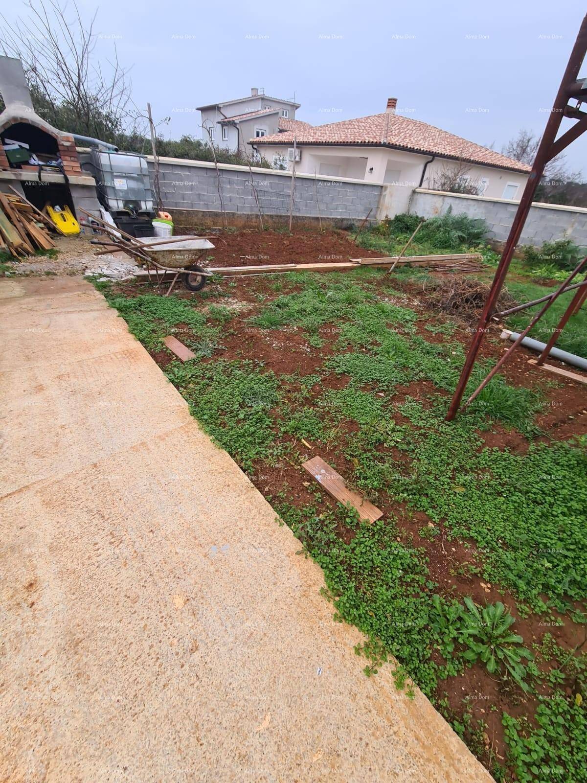 Gartenbereich im Bau mit unebenem Boden, provisorischem Weg und einem gemauerten Grill im Hintergrund.