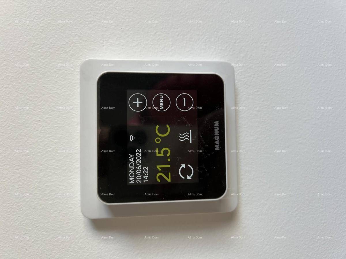 Modernes digitales Thermostat zur Steuerung der Raumtemperatur an einer weißen Wand.