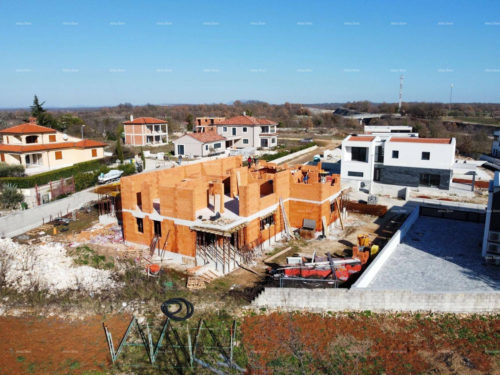 Luftaufnahme einer Baustelle mit mehreren Rohbauten und Blick auf die umliegende Landschaft.