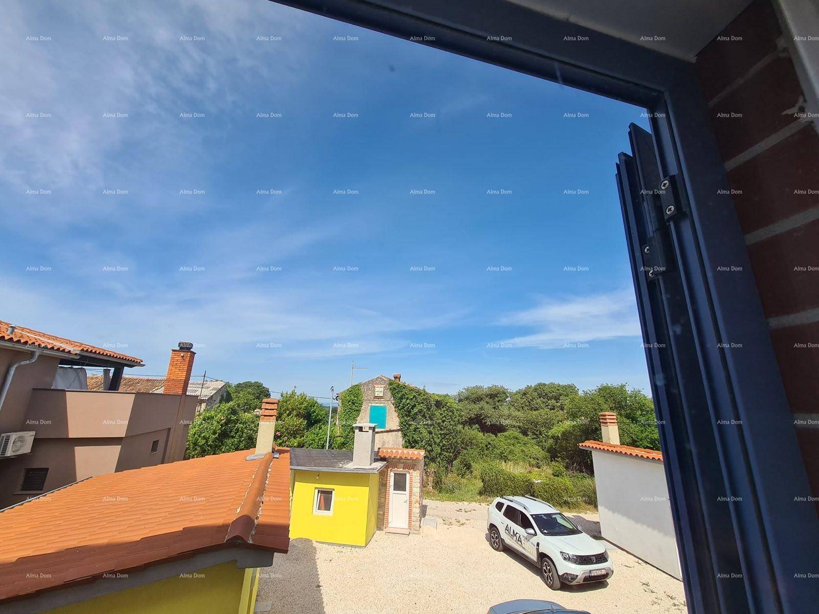 Weitblick aus dem Fenster über Dächer, grüne Bäume und einen blauen Himmel.