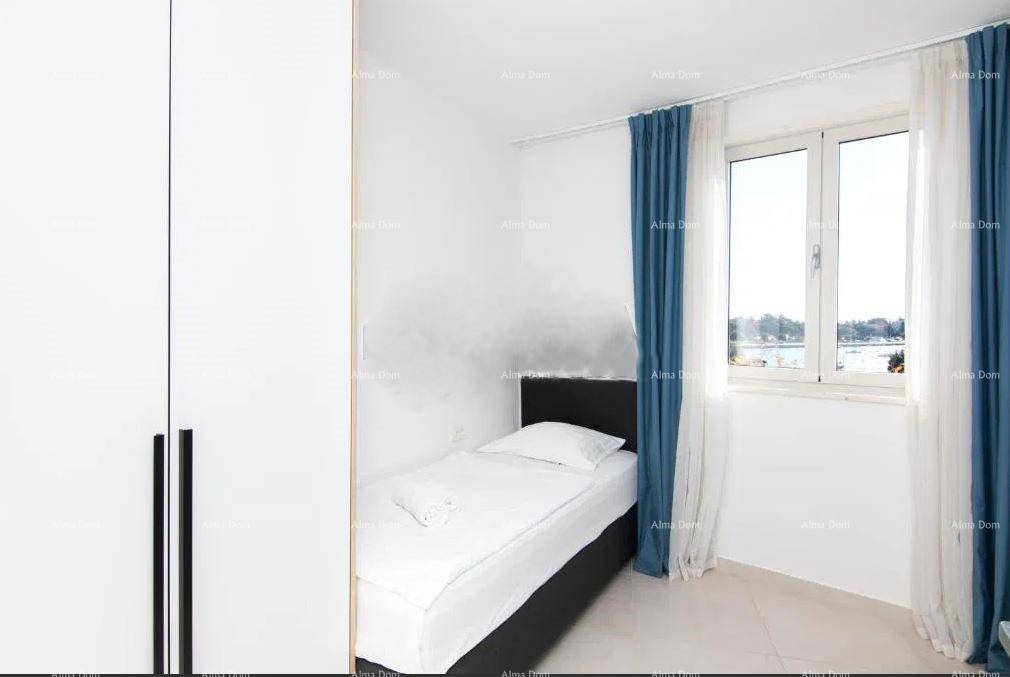 Helles Schlafzimmer mit Einzelbett, weißem Kleiderschrank und Fenster mit blauen Vorhängen.