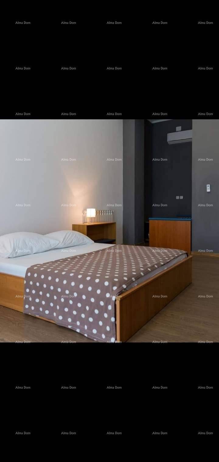 Schlafzimmer mit Holzbettrahmen, gepunkteter Bettdecke und Nachttischlampe.