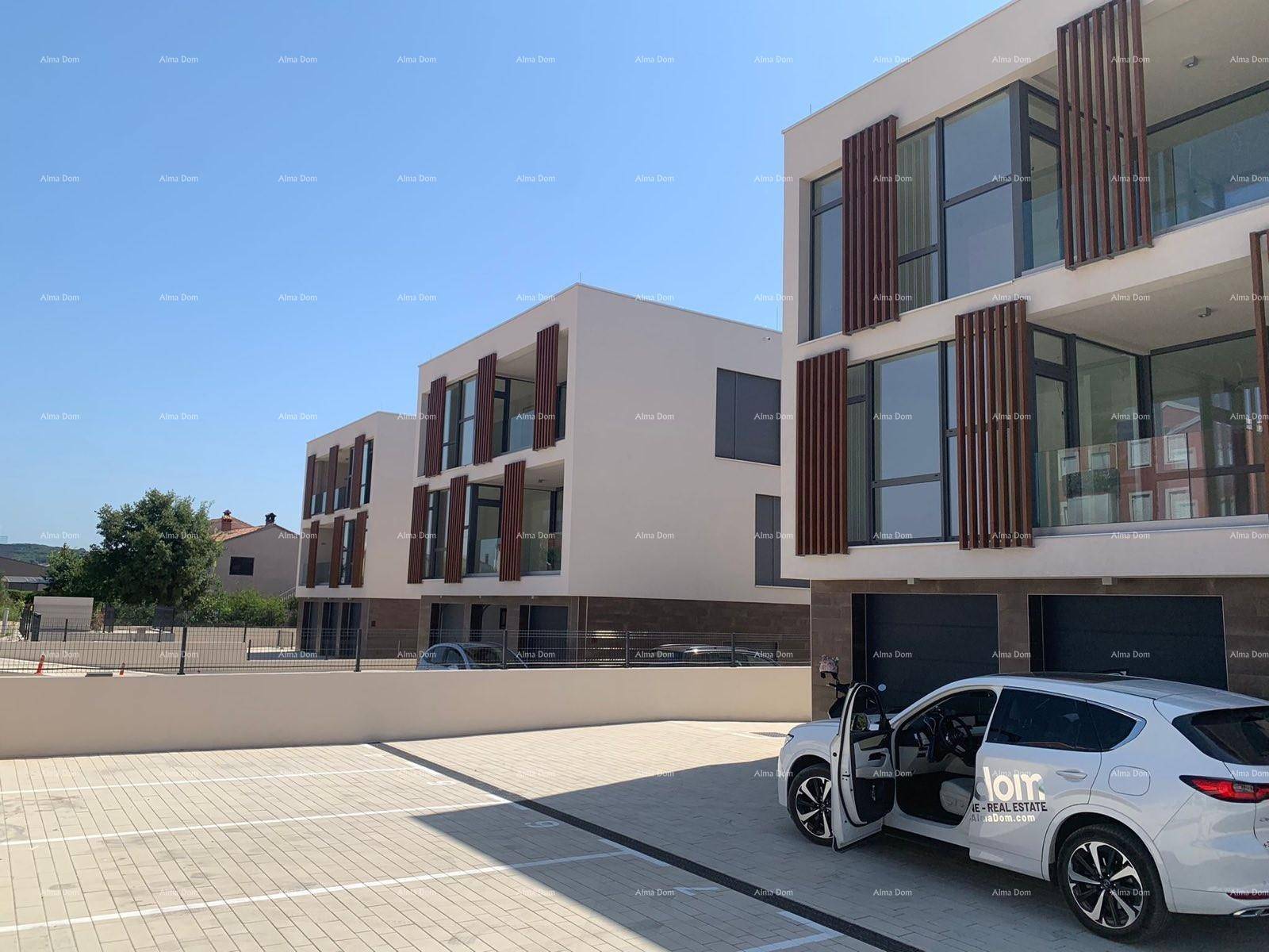 Mehrere moderne Wohngebäude mit Parkplätzen und klarem Design unter strahlendem Himmel.