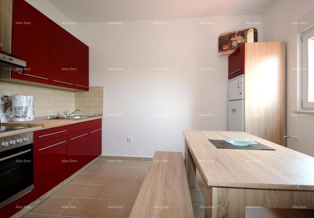Funktionale Küche mit roten Schränken, Essbereich und Fenster.