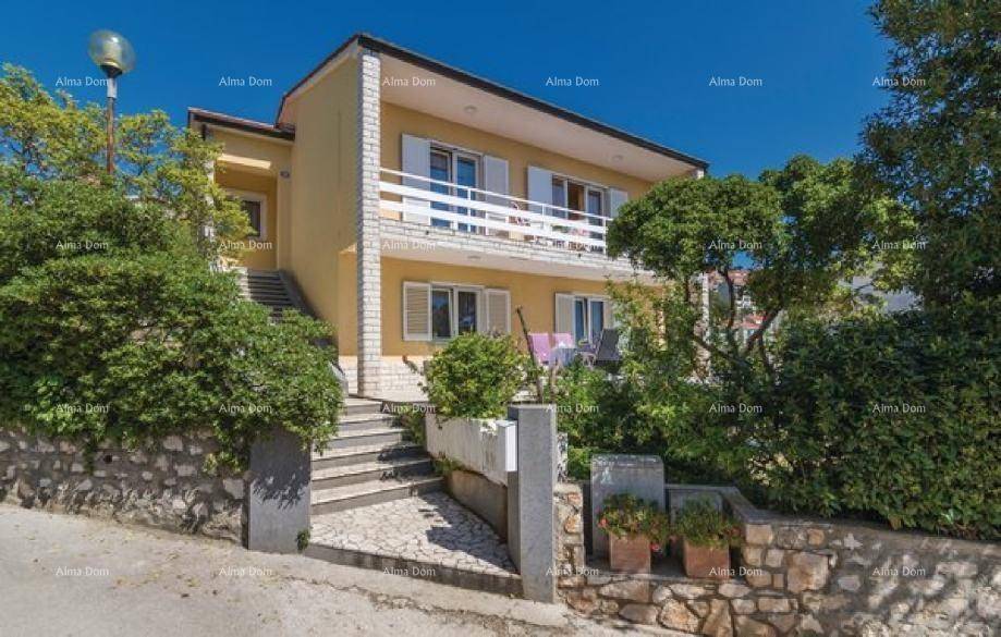 Vorderansicht des gelben Hauses mit weißen Fensterläden, Balkonen und einer Steintreppe zum Eingang.