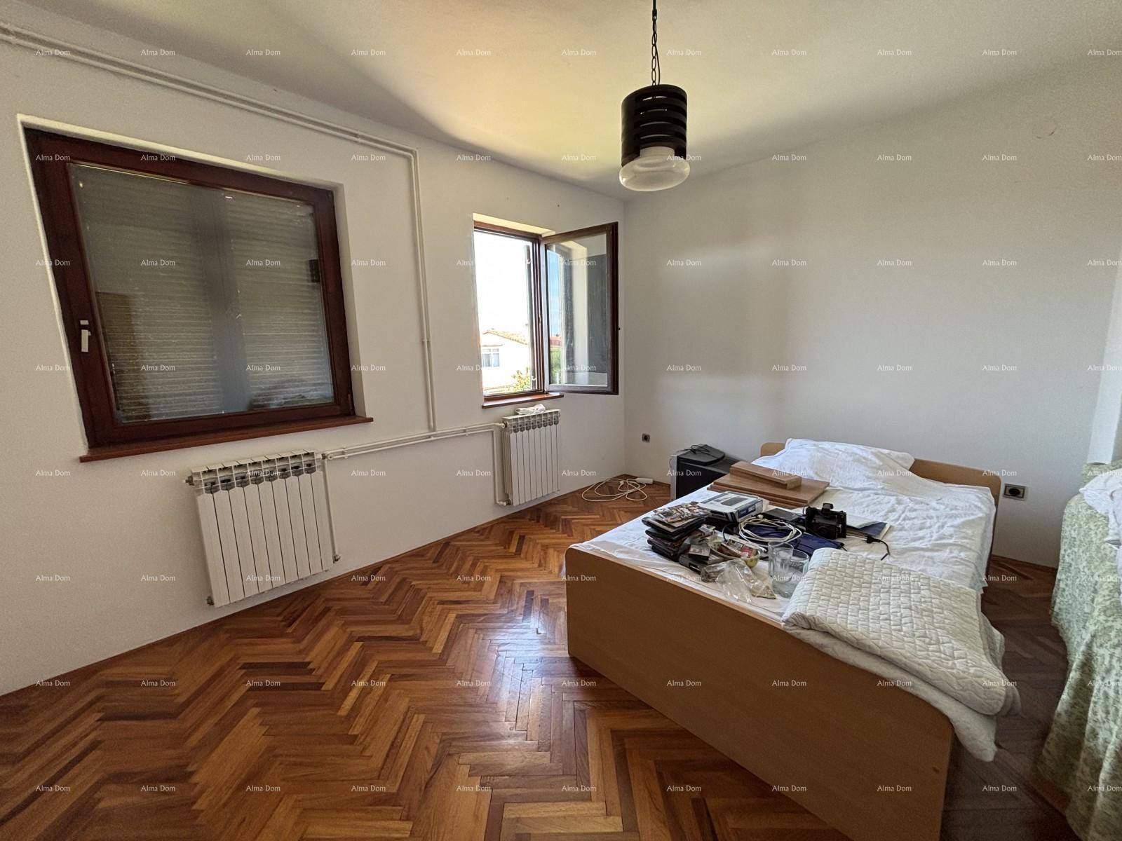 Helles Schlafzimmer mit klassischem Parkettboden, zwei Fenstern und Heizkörpern.