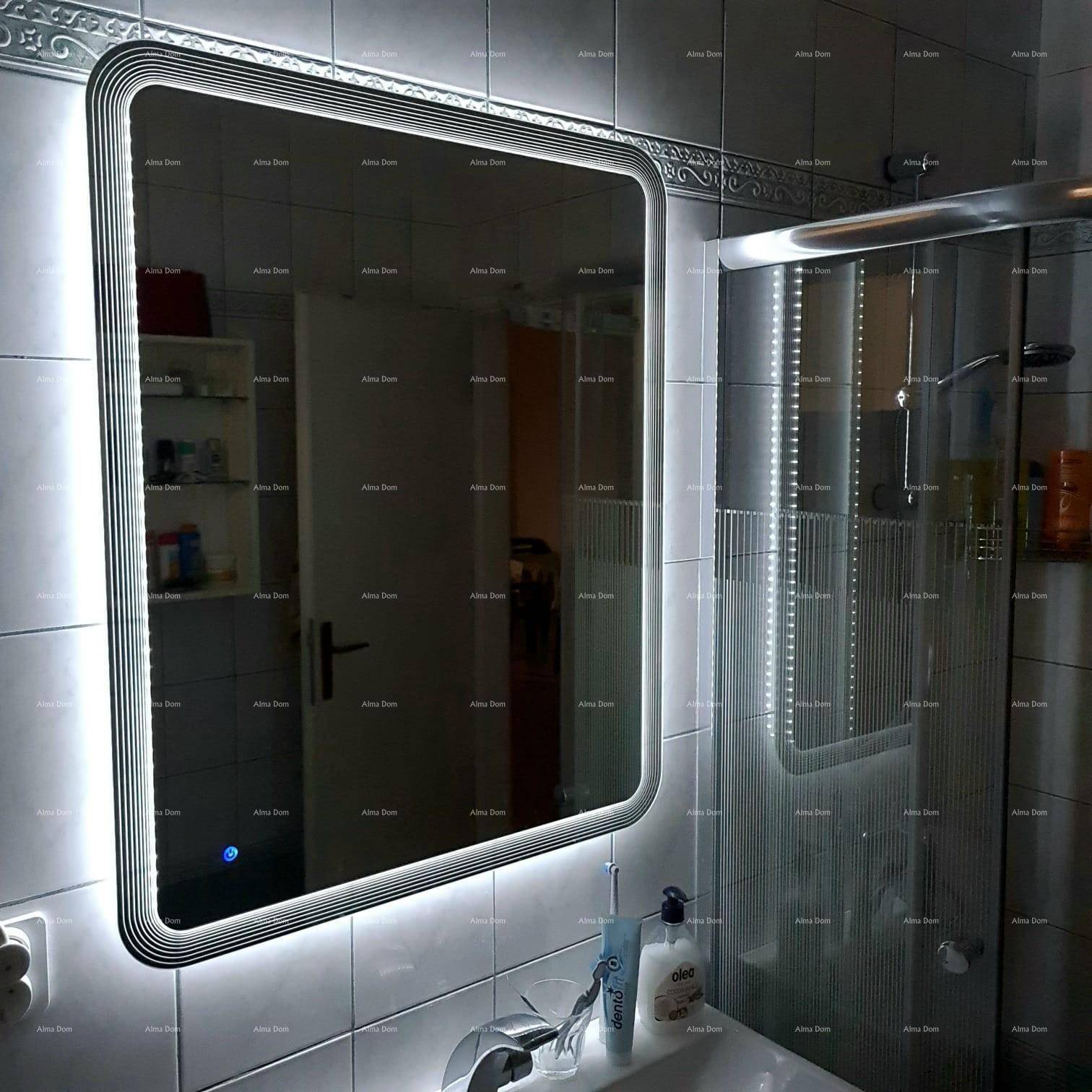 Beleuchteter Spiegel in einem modernen Badezimmer über einem Waschbecken mit Armatur.