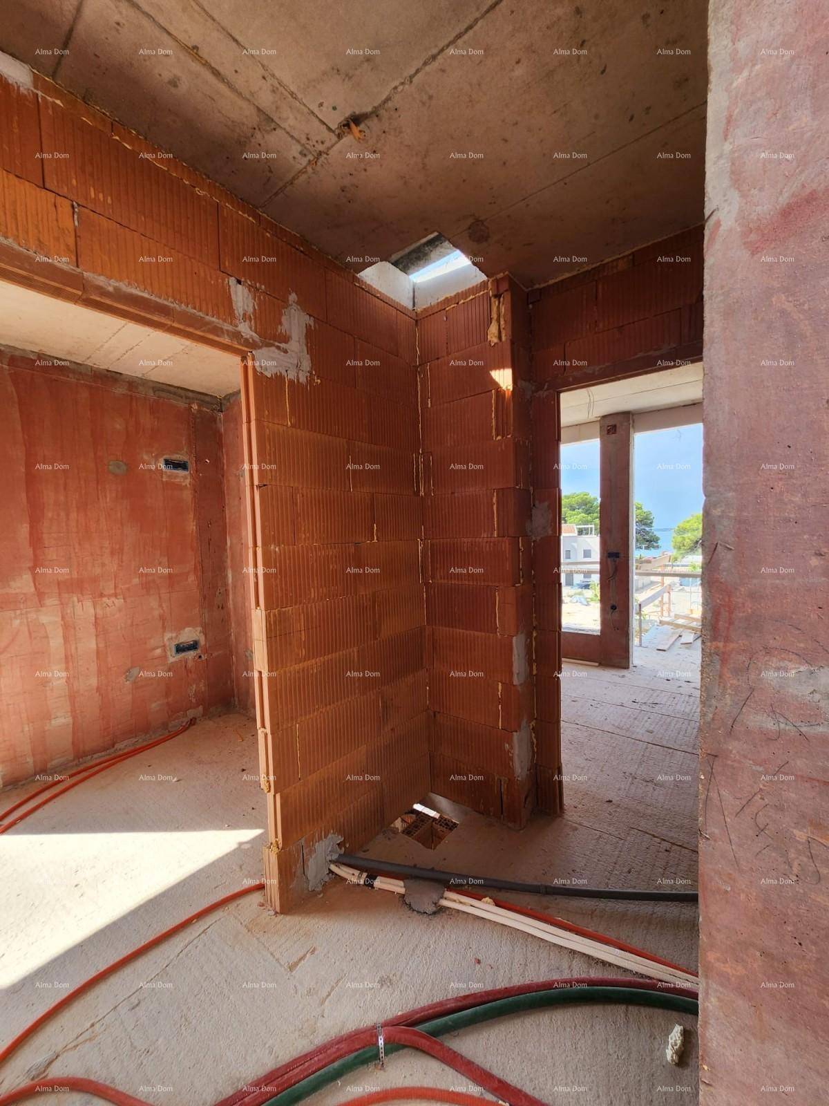 Ecke eines Raumes im Rohbau mit Ziegelwänden und sichtbaren Elektroinstallationen auf dem Boden.