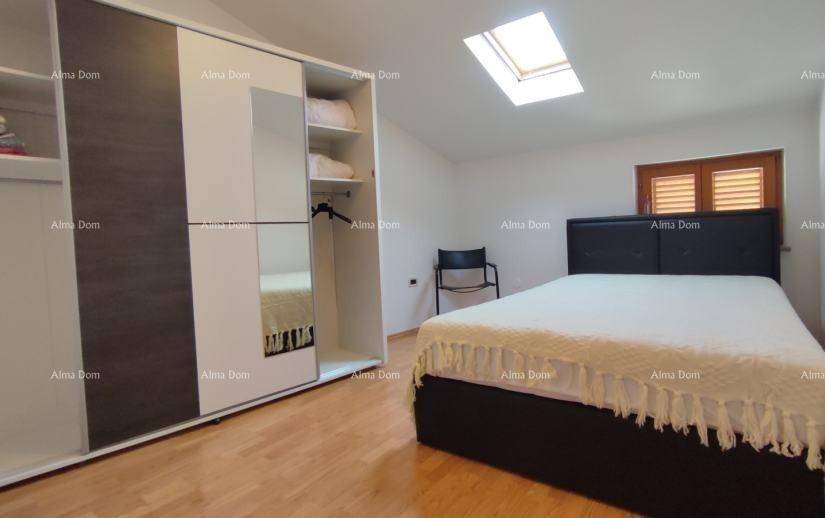 Helles Schlafzimmer mit Bett, großem Kleiderschrank und Dachfenster.