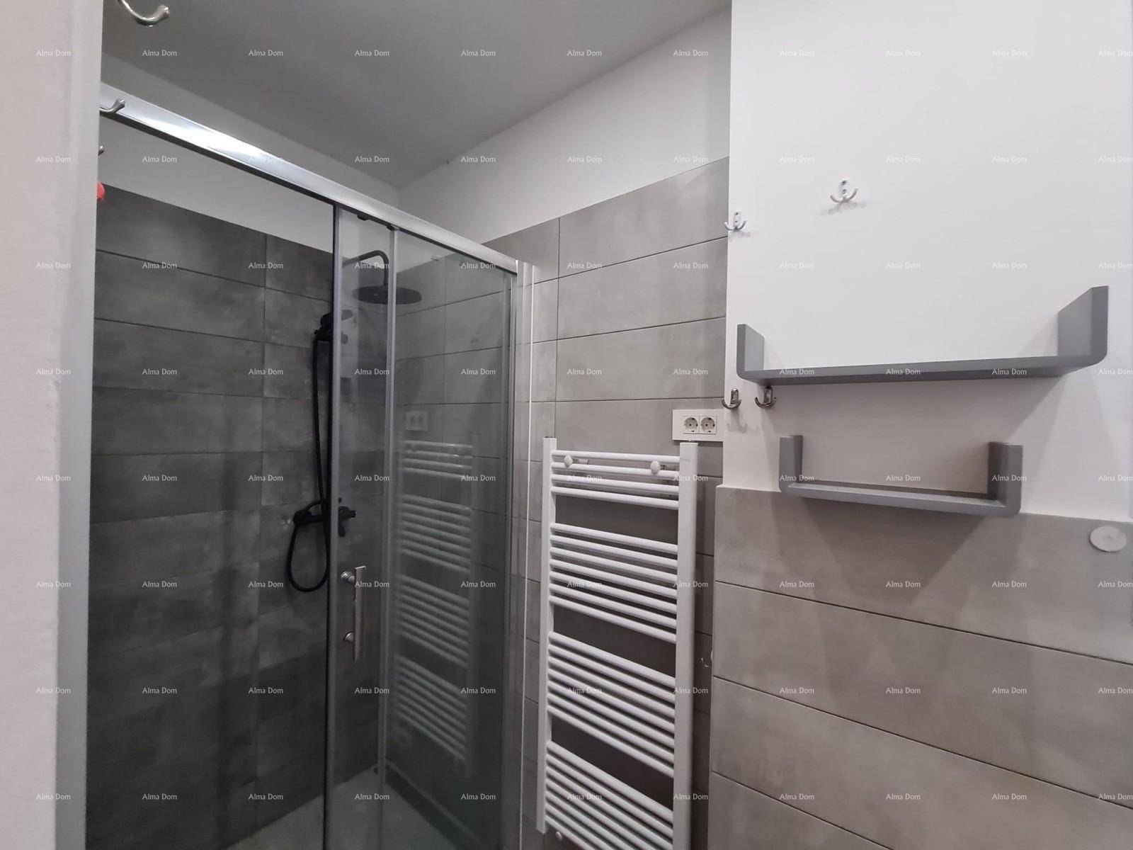 Modernes Badezimmer mit Duschkabine, grauen Fliesen und beheiztem Handtuchhalter.