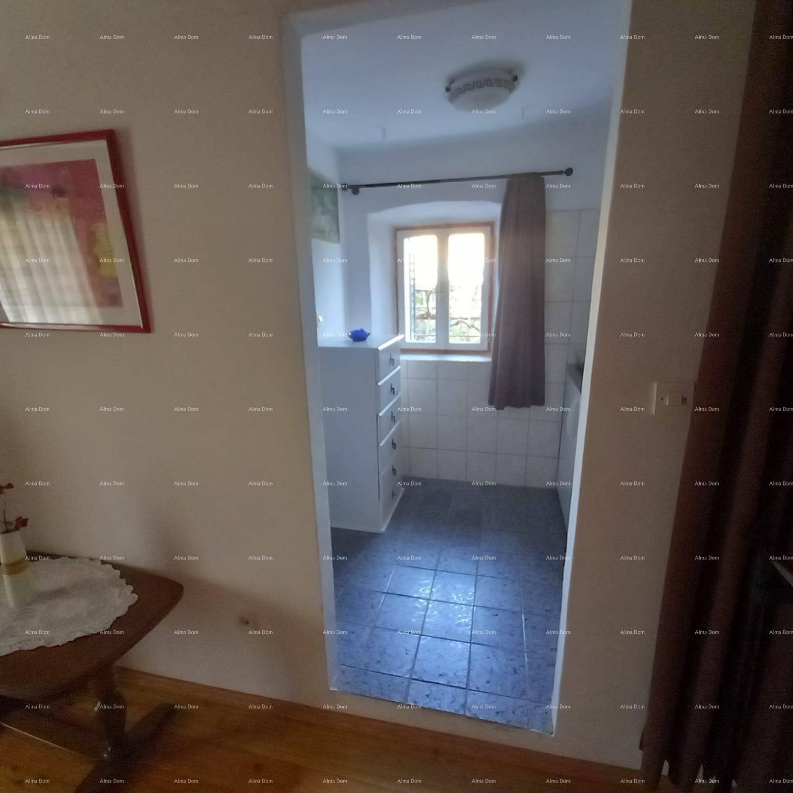 Kleines Badezimmer mit Fliesenboden, einem Fenster und einfacher Einrichtung, das Tageslicht hereinlässt.