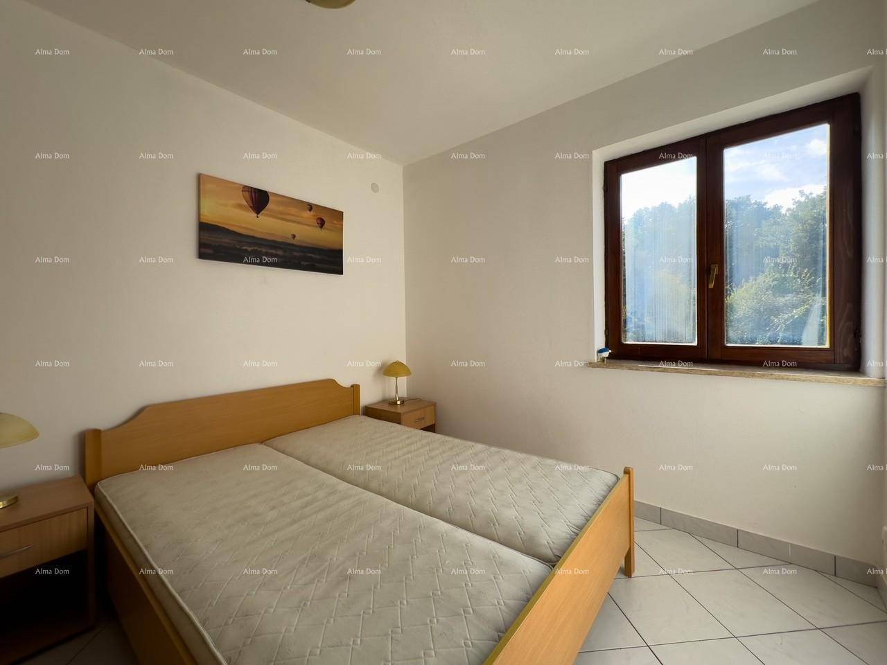 Schlafzimmer mit zwei Einzelbetten, Holznachttischen und einem großen Fenster mit Blick ins Grüne.