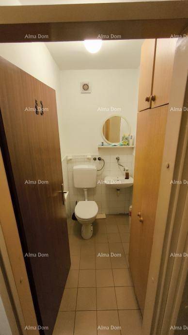 Separates WC mit Toilette, kleinem Waschbecken und Spiegel.