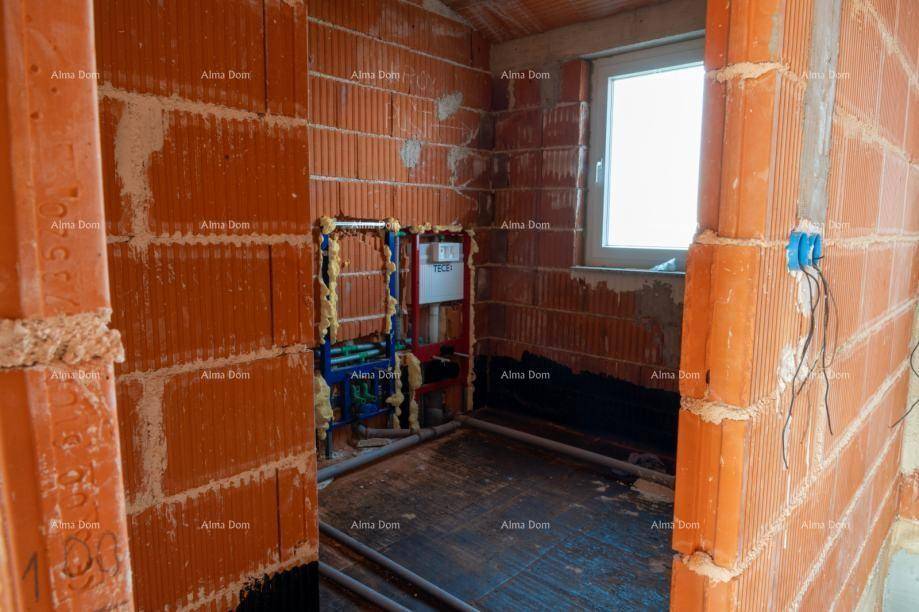 Badezimmer im Rohbau mit sichtbaren Sanitärinstallationen und einem Fenster.