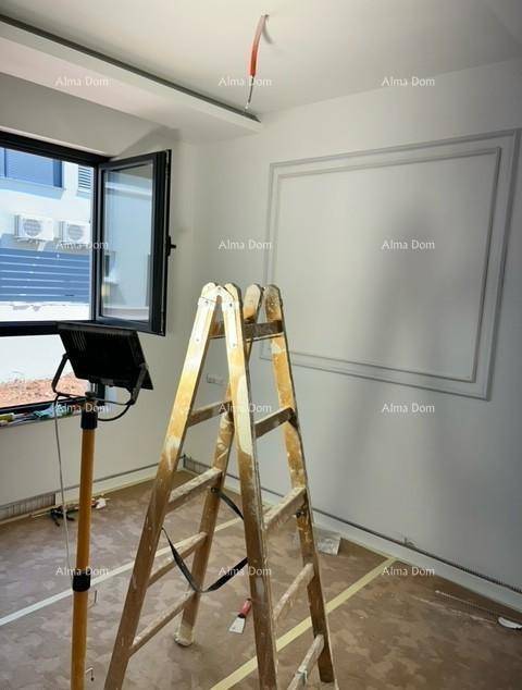 Innenraum im Bau mit weiß gestrichenen Wänden, Fenster und einer Leiter in der Mitte.