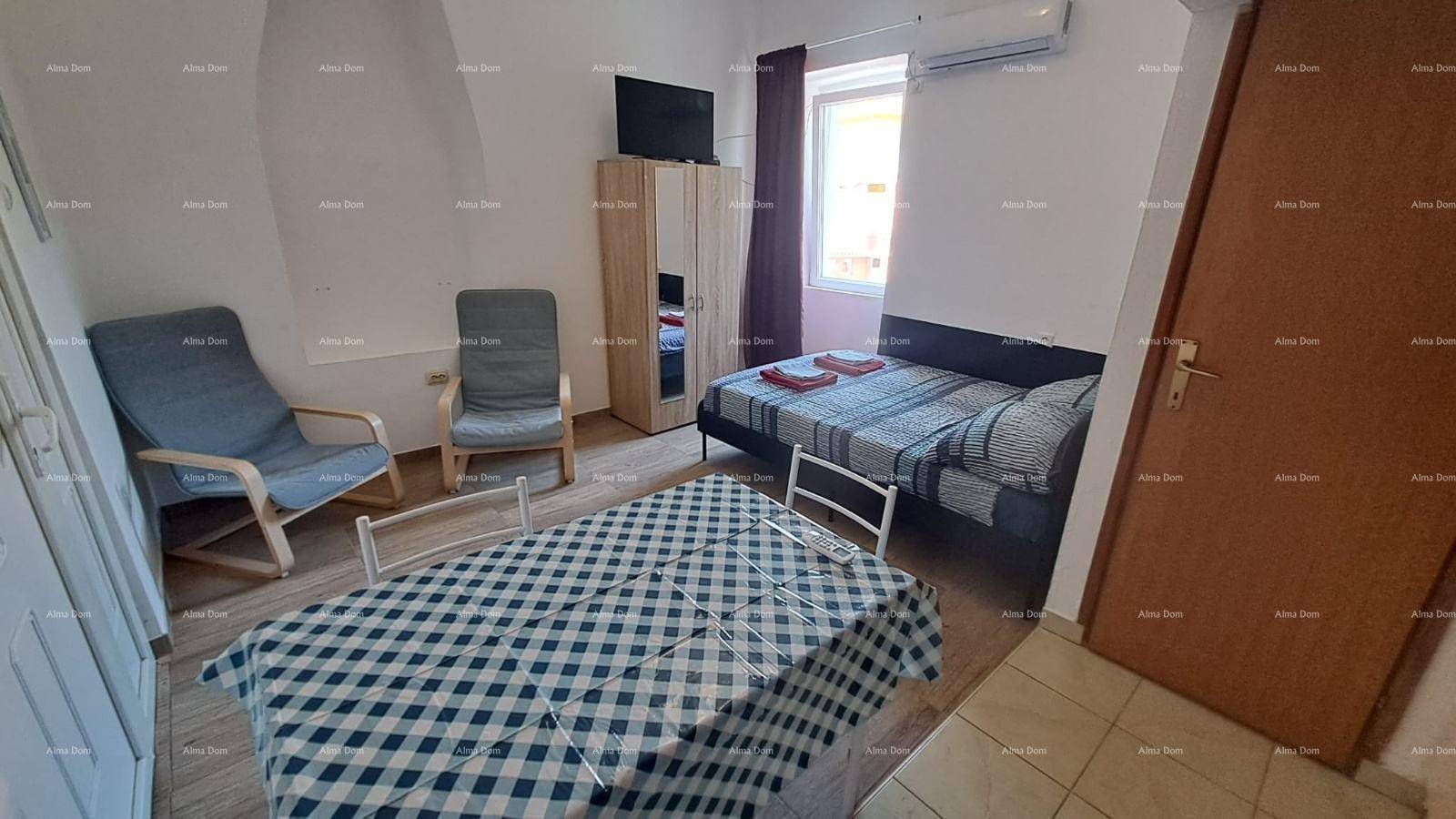 Geräumiges Studio-Apartment mit Schlafbereich, Esstisch und zwei Sesseln, hell und einladend.