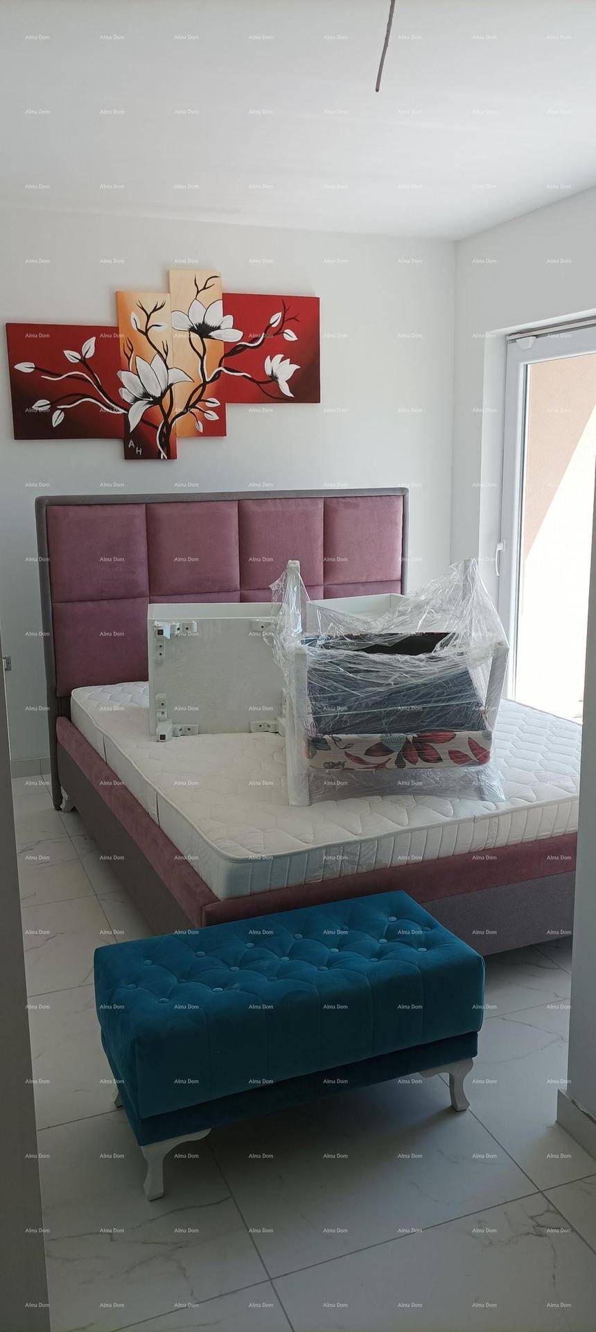 Schlafzimmer mit einem gepolsterten Bett, moderner Kunst an der Wand und Fliesenboden.