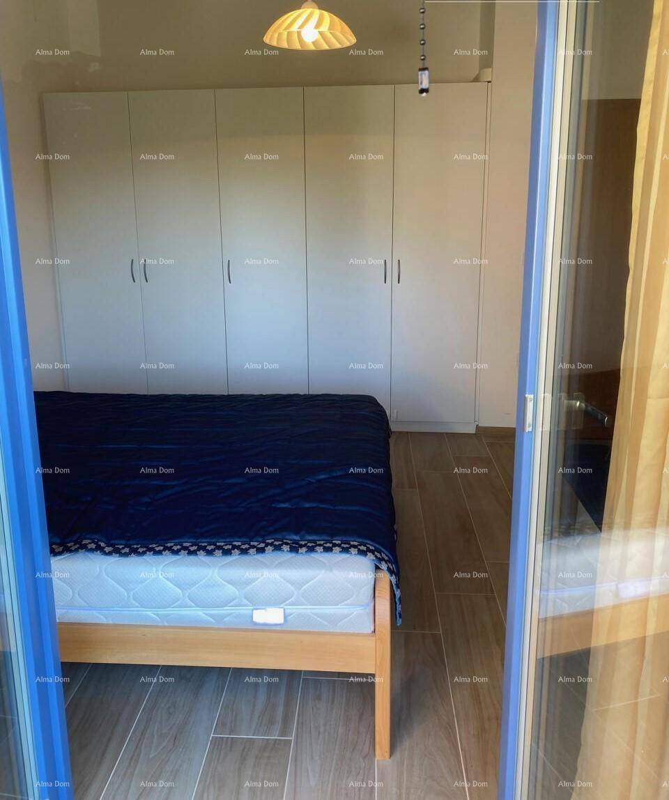 Helles Schlafzimmer mit Holzbett und integrierten Kleiderschränken, Zugang zum Außenbereich.
