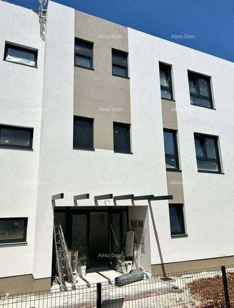 Eingangsbereich eines modernen Neubaus mit großen Glasfenstern und Baugeräten davor.
