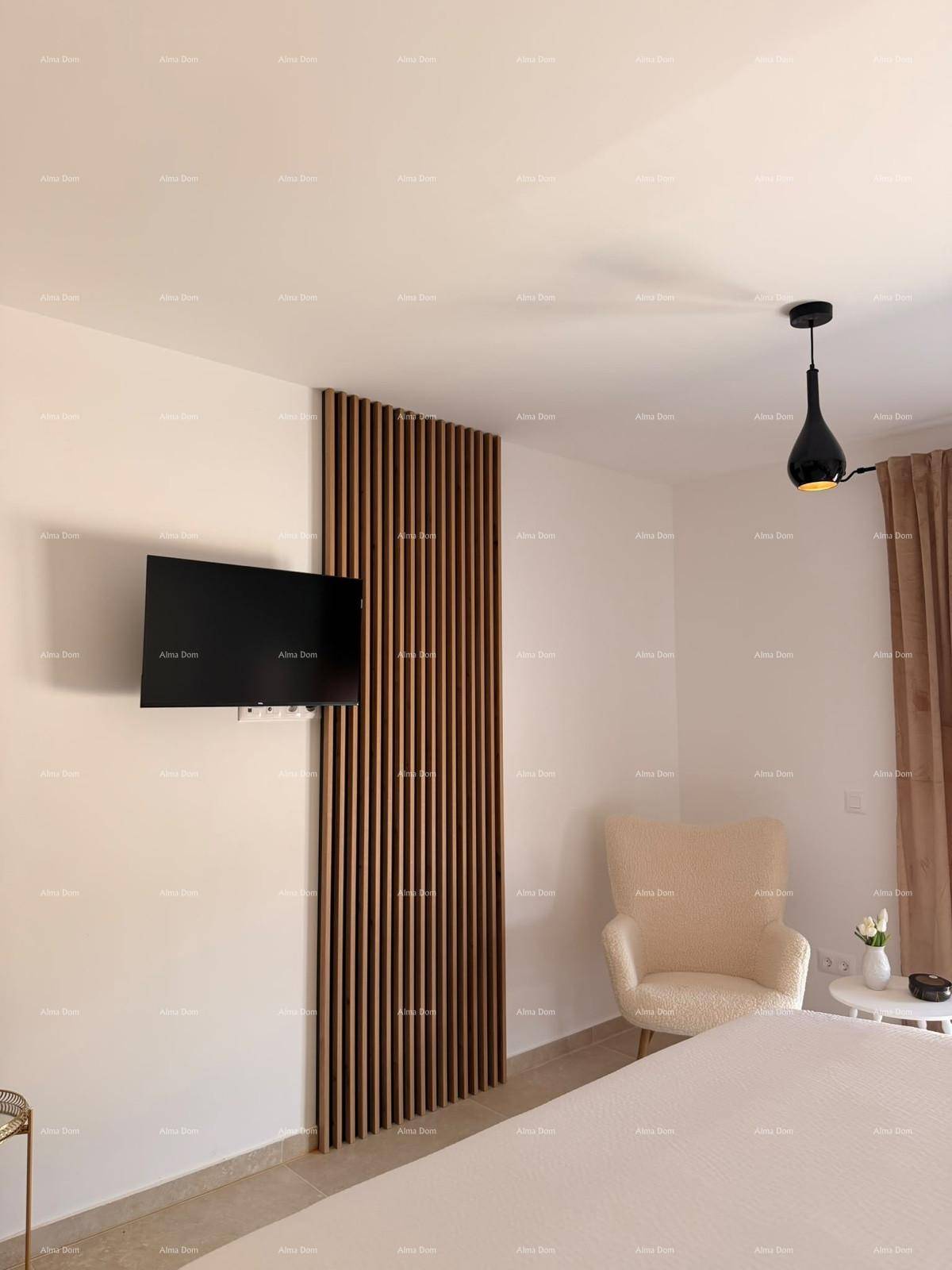 Schlafzimmer mit Wandfernseher, Holzlamellenwand und beigem Sessel.