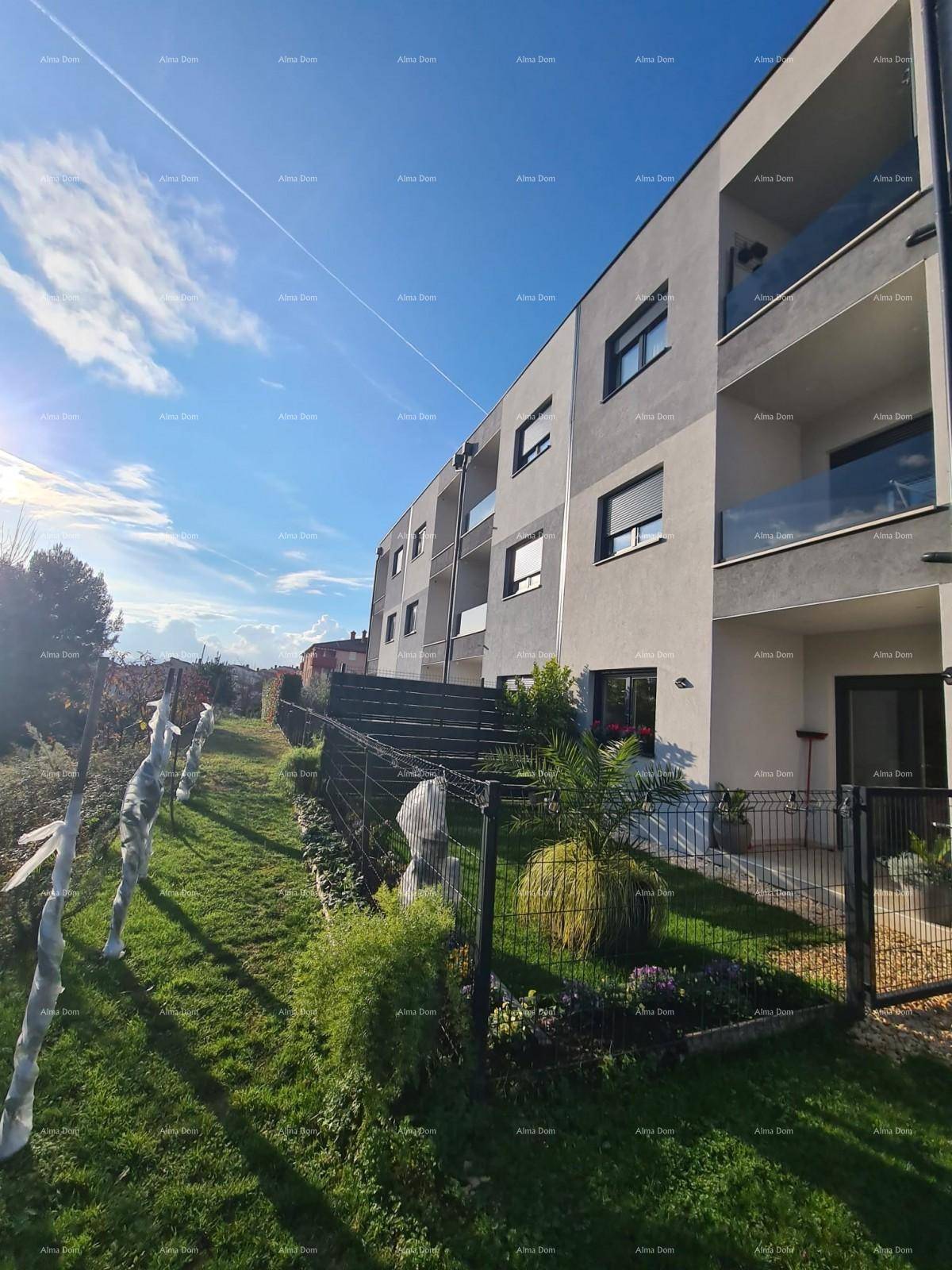 Modernes Apartmentgebäude mit Balkonen und gepflegtem Gartenbereich unter blauem Himmel.