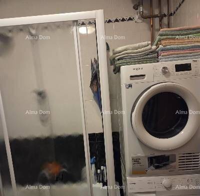 Badezimmer mit Waschmaschine, Trockner und einer Duschkabine.