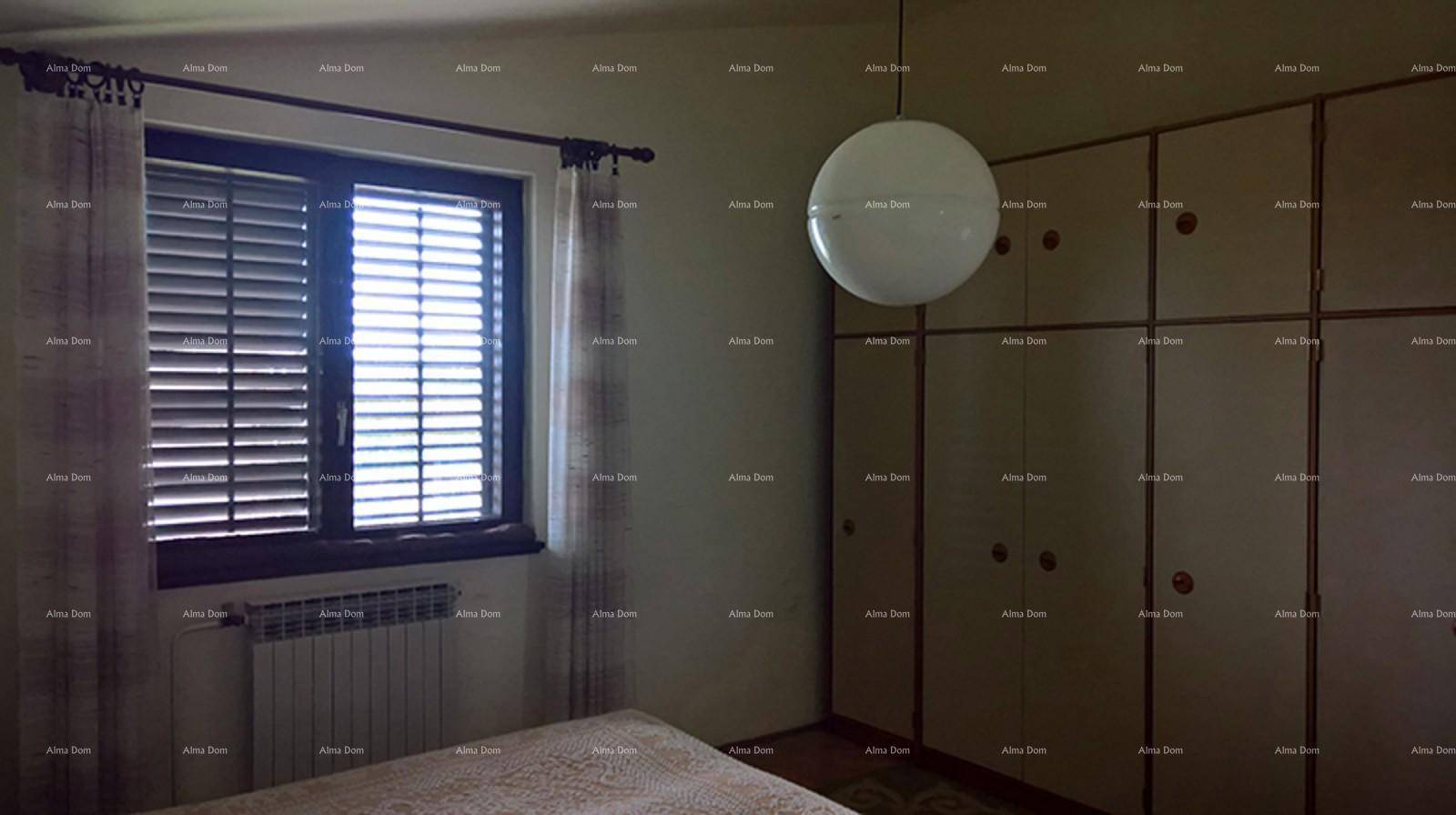 Schlafzimmer mit Einbauschränken, Fenster mit Jalousien und einer Deckenleuchte.