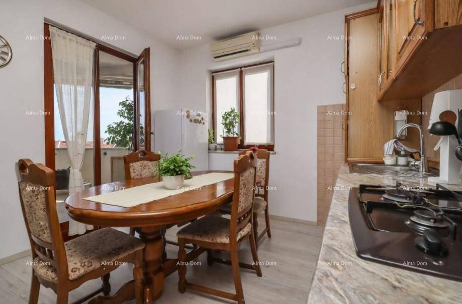Gemütliche Wohnküche mit Esstisch, Gasherd und Zugang zu einem sonnigen Balkon.