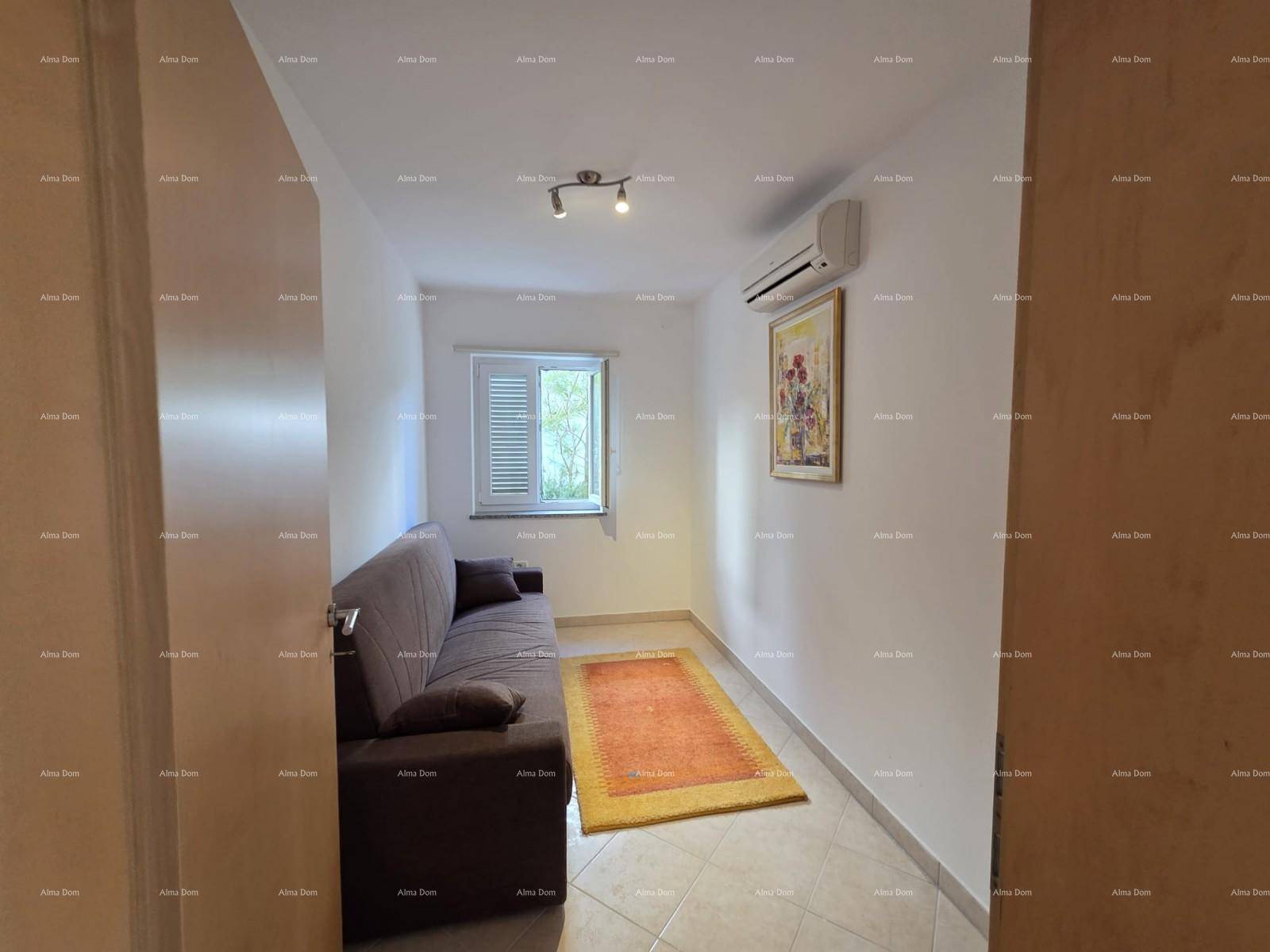 Kleines Wohnzimmer mit Sofa, Klimaanlage und Fenster mit Jalousien.