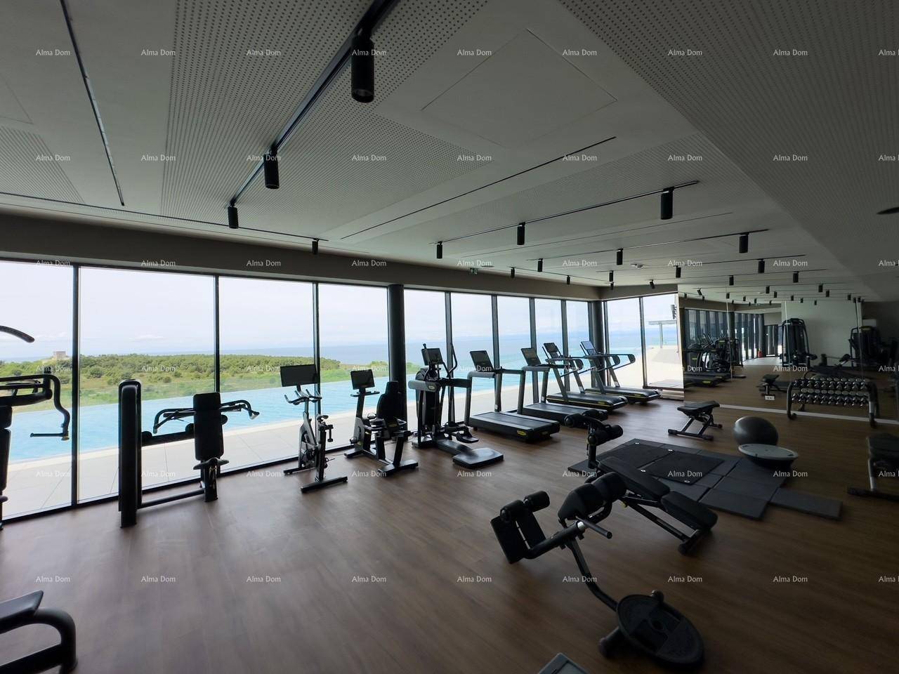 Helles Fitnessstudio mit modernen Geräten und weitem Blick auf das Meer und den angrenzenden Außenpoolbereich.