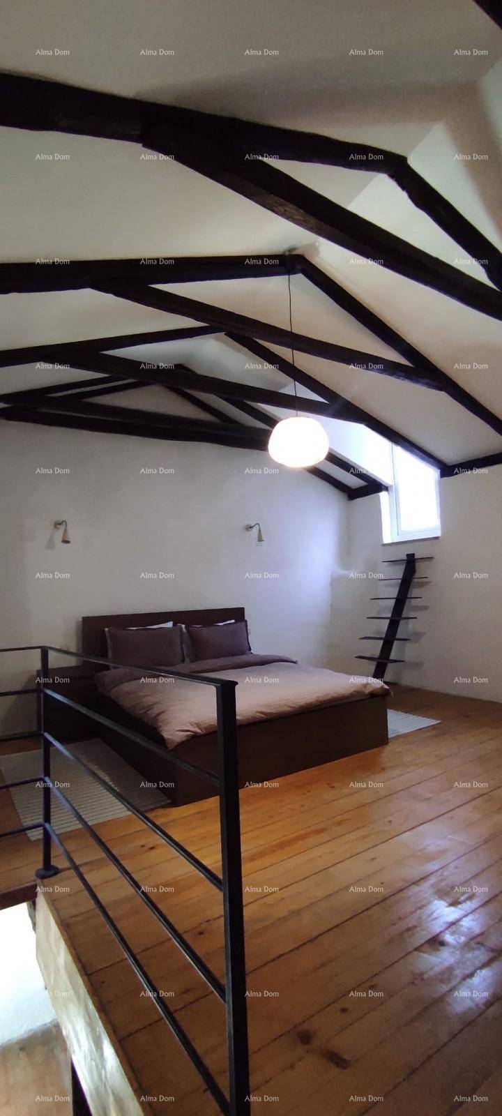 Schlafzimmer im Dachgeschoss mit markanten Holzbalken, Holzboden und einem kleinen Fenster.