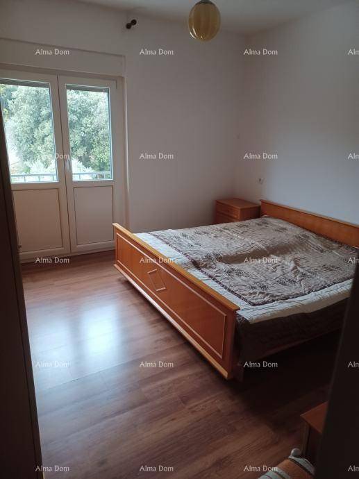 Schlafzimmer mit klassischem Holzbett, dunklem Laminatboden und Zugang zu einem Balkon oder einer Terrasse.