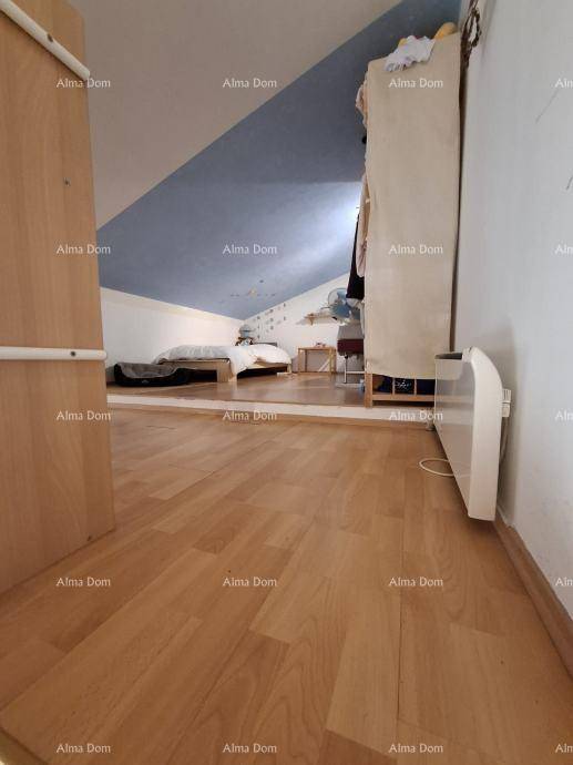Flur mit Holzboden, der zu einem Schlafbereich im Dachgeschoss mit schrägen Wänden führt.